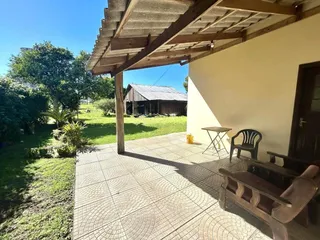 Pátio externo com piso de concreto e estrutura de madeira sob um pergolado.