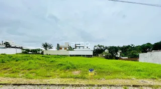Vista externa de uma propriedade com gramado verde e um edifício ao fundo.
