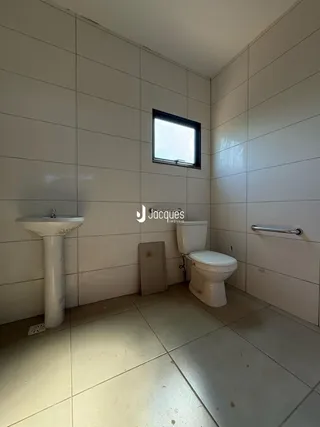 Foto de um banheiro com piso de cerâmica e azulejos brancos.