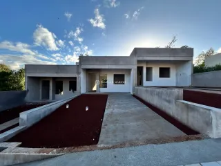Fachada externa de uma residência moderna em Lajeado, Brasil, com paisagismo em terra vermelha.