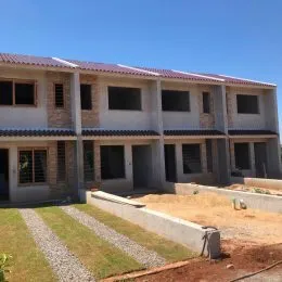 Vista externa do terreno com gramado e muro de contenção.