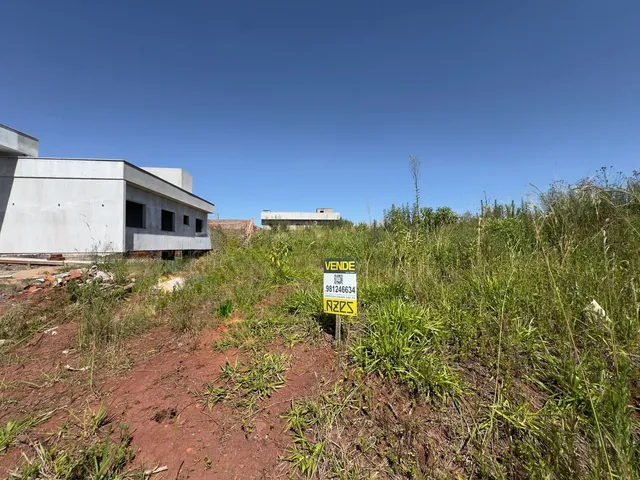 Foto da fachada de uma construção branca em um terreno com vegetação alta.