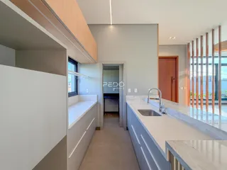 Vista interna de uma cozinha moderna com armários e bancadas claras.