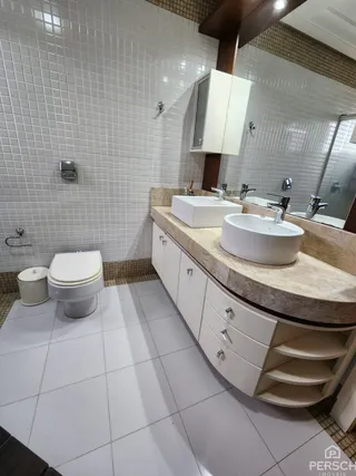 Banheiro com bancada dupla e revestimento branco nas paredes.