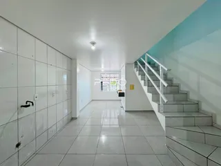 Corredor interno com piso de cerâmica e escadaria em um imóvel.
