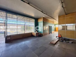 Vista interna de um espaço amplo com grandes janelas industriais.