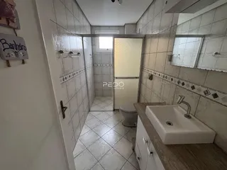 Interior de um banheiro com revestimento de azulejos brancos e piso de cerâmica.