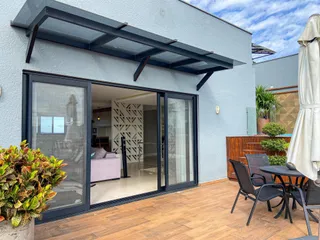 Fachada de uma casa com portas de vidro que dão acesso a uma área externa com deck de madeira.