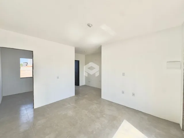 Vista de um corredor interno com paredes brancas e piso de concreto.