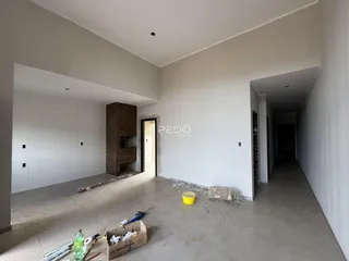 Interior de uma sala em construção com paredes brancas e piso de concreto.