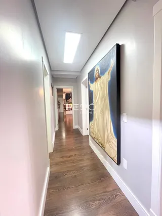 Um corredor interno com piso de madeira e paredes brancas.