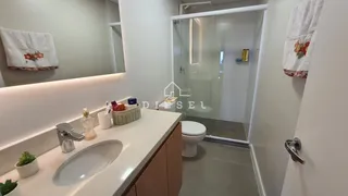 Interior de um banheiro moderno com box de vidro e bancada branca.