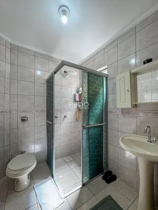Foto interna de um banheiro com piso de cerâmica e box de vidro.