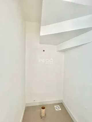 Parede interna branca com molduras de teto em um imóvel.