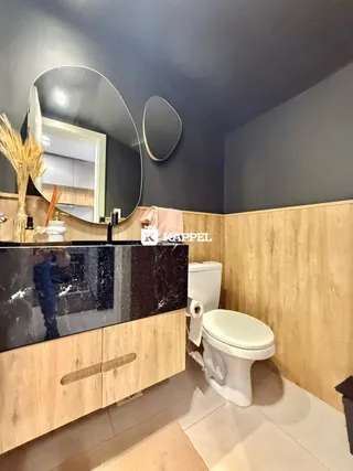 Foto de um banheiro com bancada escura e revestimento de madeira nas paredes.