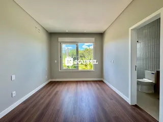 Sala de estar com piso de madeira e janela que oferece vista para o exterior.