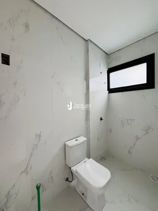Um banheiro moderno com paredes de mármore branco e piso claro.