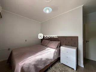 Quarto com cama grande e cabeceira estofada em um ambiente claro.