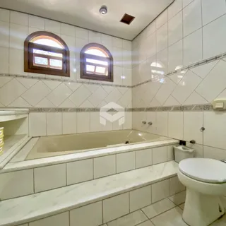 Foto de um banheiro com banheira e revestimento cerâmico branco.