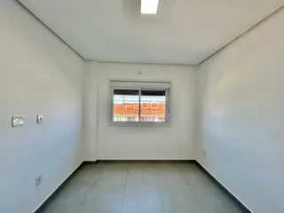 Vista de um corredor interno com paredes brancas e piso de cerâmica.