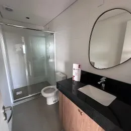 Foto de um banheiro com piso claro e espelho grande na parede.