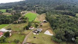 Vista aérea de uma propriedade rural com campos e vegetação densa.