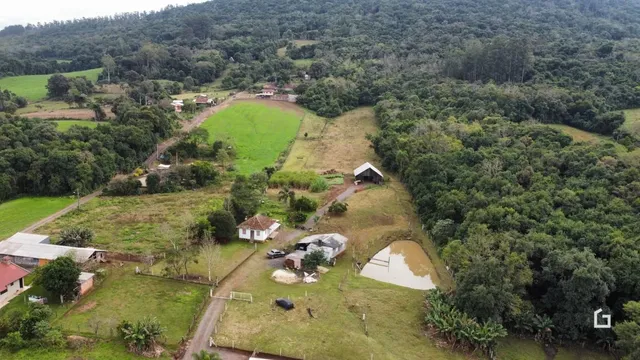 Vista aérea de uma propriedade rural com campos e vegetação densa.