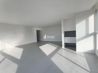 Interior de uma sala ampla com paredes brancas e piso cinza claro.