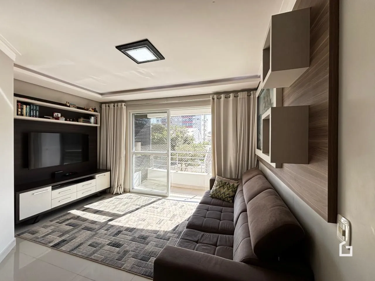 Sala de estar com sofá e televisão em um apartamento.
