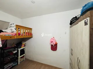 Quarto com cama de madeira e armário branco em ambiente interno.
