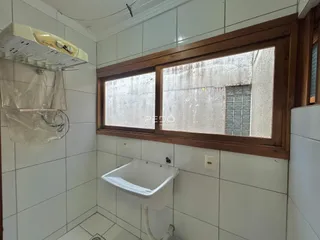 Foto de um banheiro com revestimento cerâmico branco e janela.