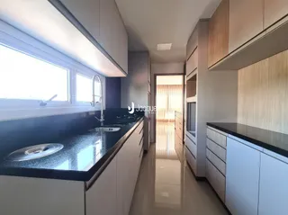 Vista de um corredor moderno com armários em madeira e bancadas escuras.