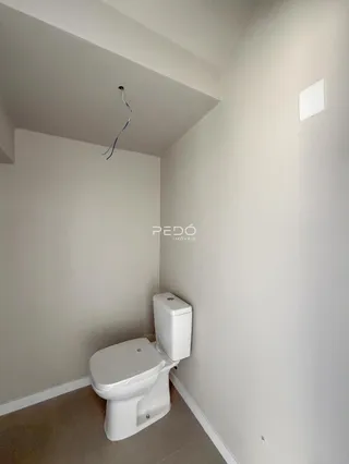 Foto interna de um ambiente com vaso sanitário e paredes brancas.