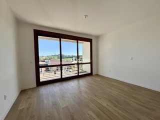 Sala de estar com piso de madeira e vista para o exterior.