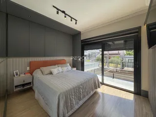 Quarto com cama e portas de vidro que dão acesso ao exterior.