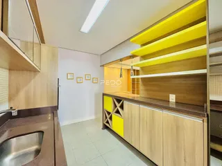 Foto de uma cozinha moderna com armários de madeira clara e detalhes amarelos.