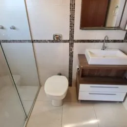 Foto de um banheiro com revestimento de azulejos e um vaso sanitário branco.