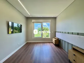 Quarto com piso de madeira e janela mostrando a vegetação externa.