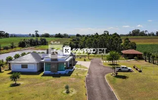 Vista externa de uma casa com jardim e paisagem rural.