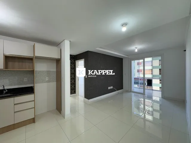 Sala de estar com cozinha integrada e piso de porcelanato claro em um imóvel.