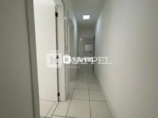 Foto de um corredor interno com paredes brancas e piso claro.