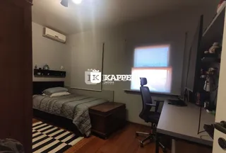 Quarto com cama e escrivaninha em ambiente interno com piso de madeira.