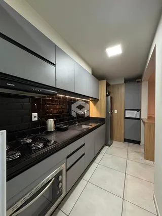 Uma cozinha moderna com armários escuros e bancadas pretas.