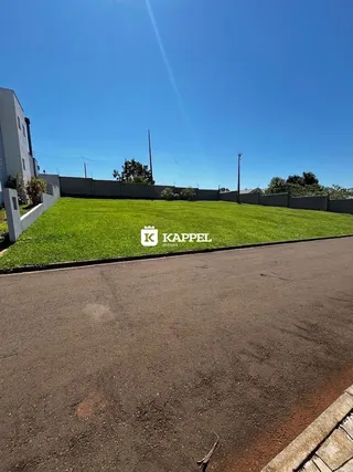 Vista externa do terreno com gramado verde e área pavimentada.