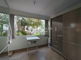 Sala de estar com grandes janelas que dão vista para a vegetação externa.