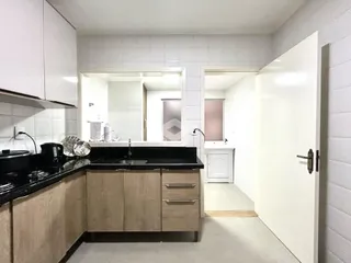 Interior da cozinha com armários de madeira e revestimento de azulejos brancos.