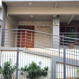 Vista externa de um prédio com grade metálica e vegetação.