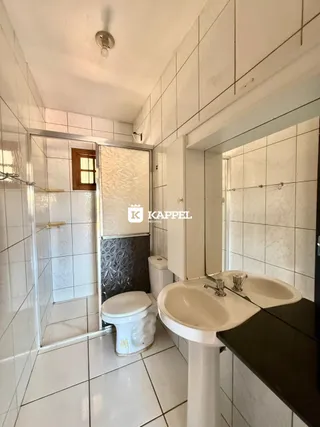 Foto interna de um banheiro com revestimento de azulejos brancos.