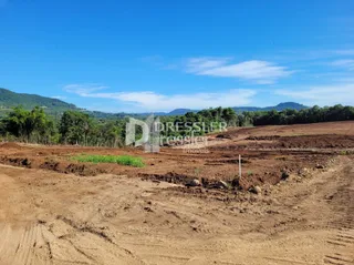 Terreno de terra arada em paisagem aberta sob céu azul.