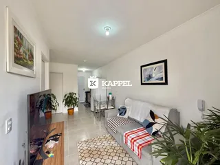 Sala de estar com sofá e mesa de jantar em um apartamento claro.